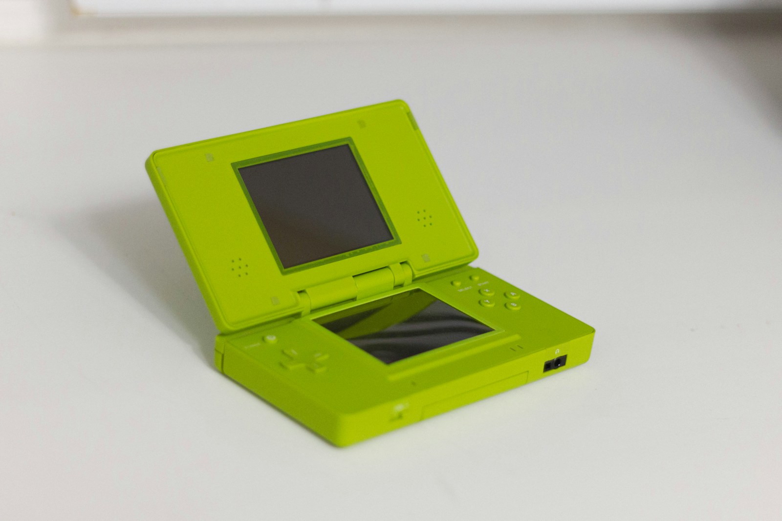 A lime green nintendo ds is displayed open.